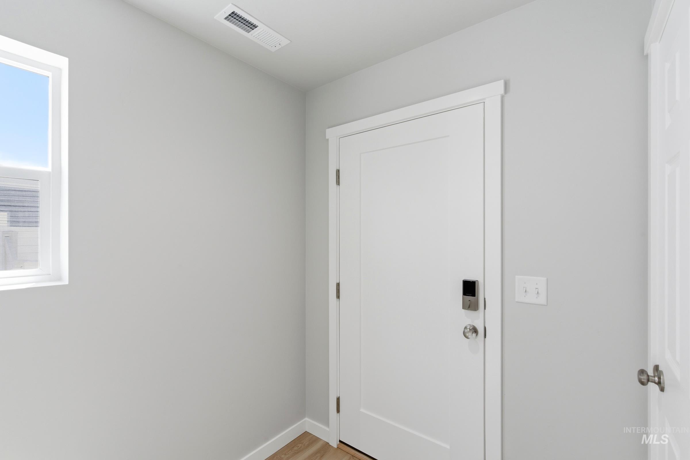 2374 West Fallon Loop Nampa, ID 83651 - Photo 2 of 24 Entryway featuring a white paneled door with a smart lock, light gray walls, white trim, and wood-finish flooring