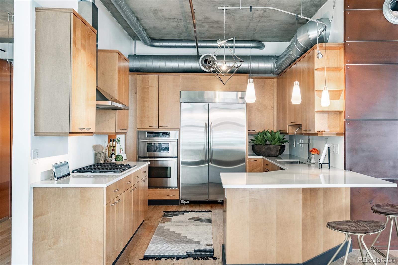 1890 Wynkoop Street, Unit 604 Denver, CO 80202 - Photo 13 of 26 a kitchen with stainless steel appliances kitchen island granite countertop a sink a stove and a refrigerator