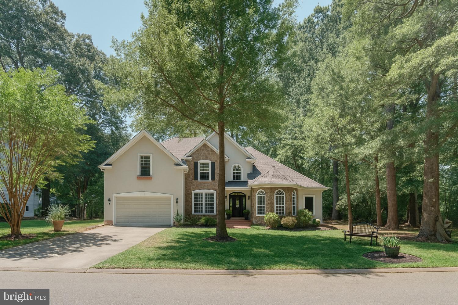 a front of a white house with a yard and large trees