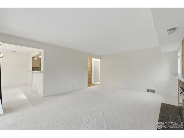 a view of an empty room with a fireplace and a window