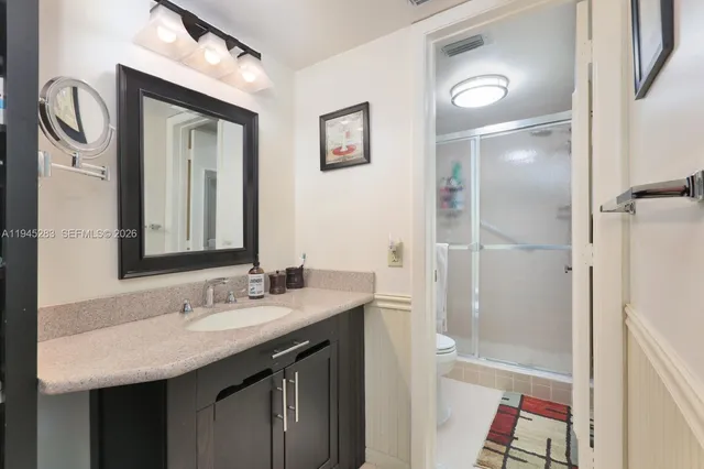 a bathroom with a granite countertop sink mirror and a shower