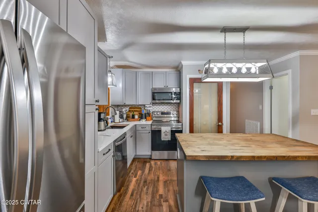 a kitchen with kitchen island granite countertop stainless steel appliances a refrigerator oven a sink a stove and a refrigerator