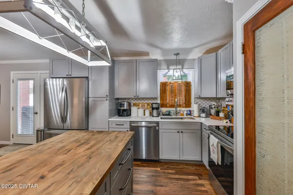 a kitchen with stainless steel appliances granite countertop a stove top oven a sink dishwasher a refrigerator and cabinets with wooden floor