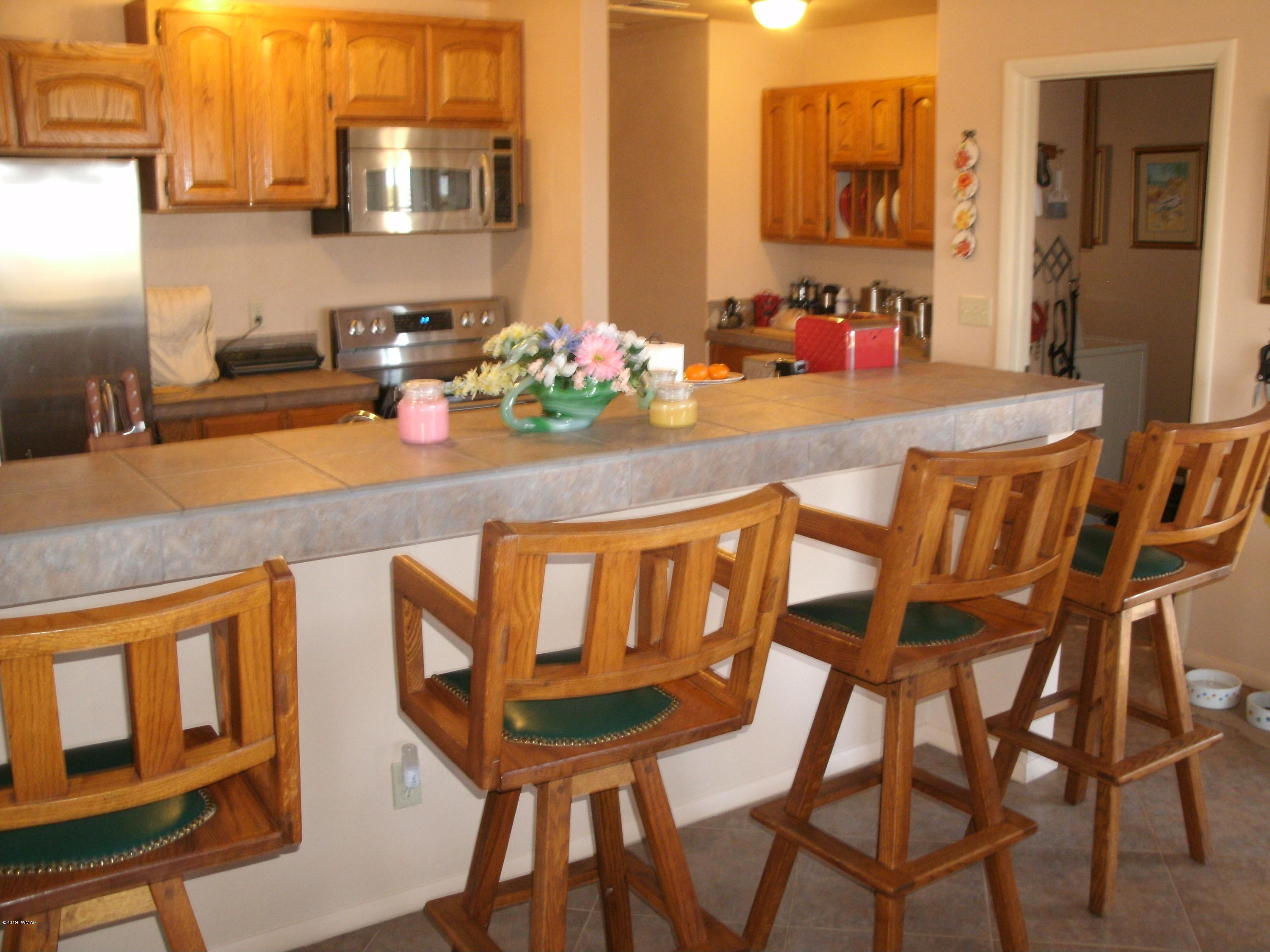 4078 East Pinto Road Snowflake, AZ 85937 - Photo 21 of 49 a kitchen with a dining table chairs cabinets and stainless steel appliances