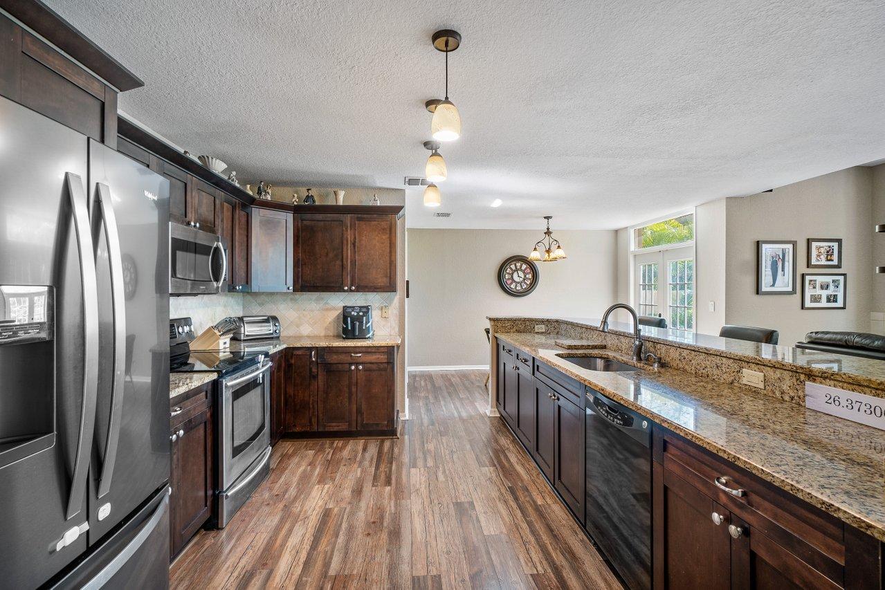 10921 Haydn Drive Boca Raton, FL 33498 - Photo 10 of 45 a kitchen with granite countertop stainless steel appliances a sink stove top oven and refrigerator