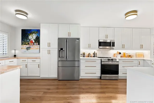 a kitchen with granite countertop a sink stainless steel appliances and white cabinets