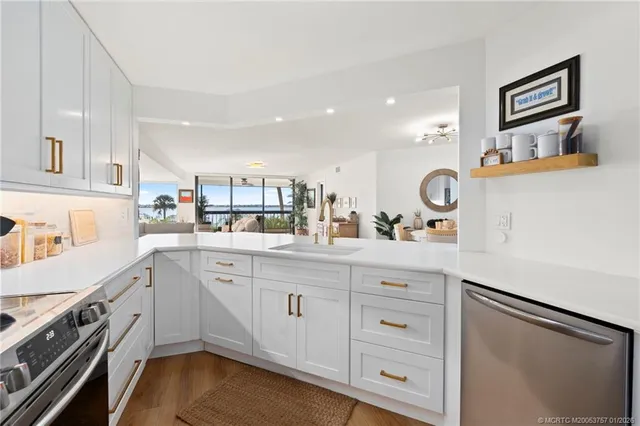 a kitchen with stainless steel appliances granite countertop a table chairs refrigerator and sink