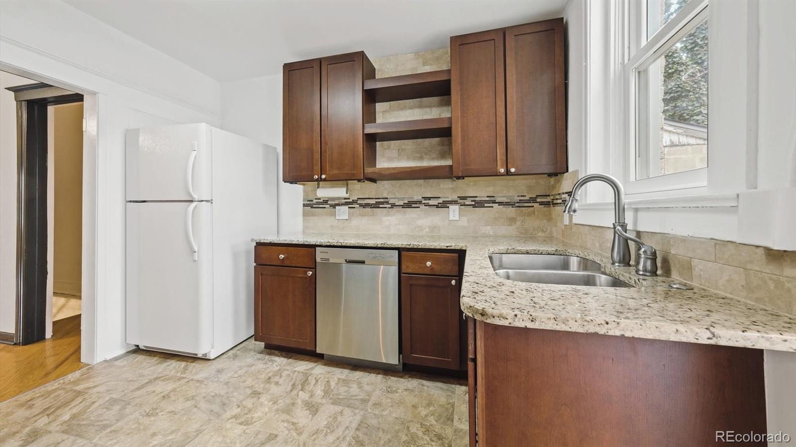 553 Logan Street Denver, CO 80203 - Photo 18 of 38 a kitchen with kitchen island granite countertop cabinets and refrigerator