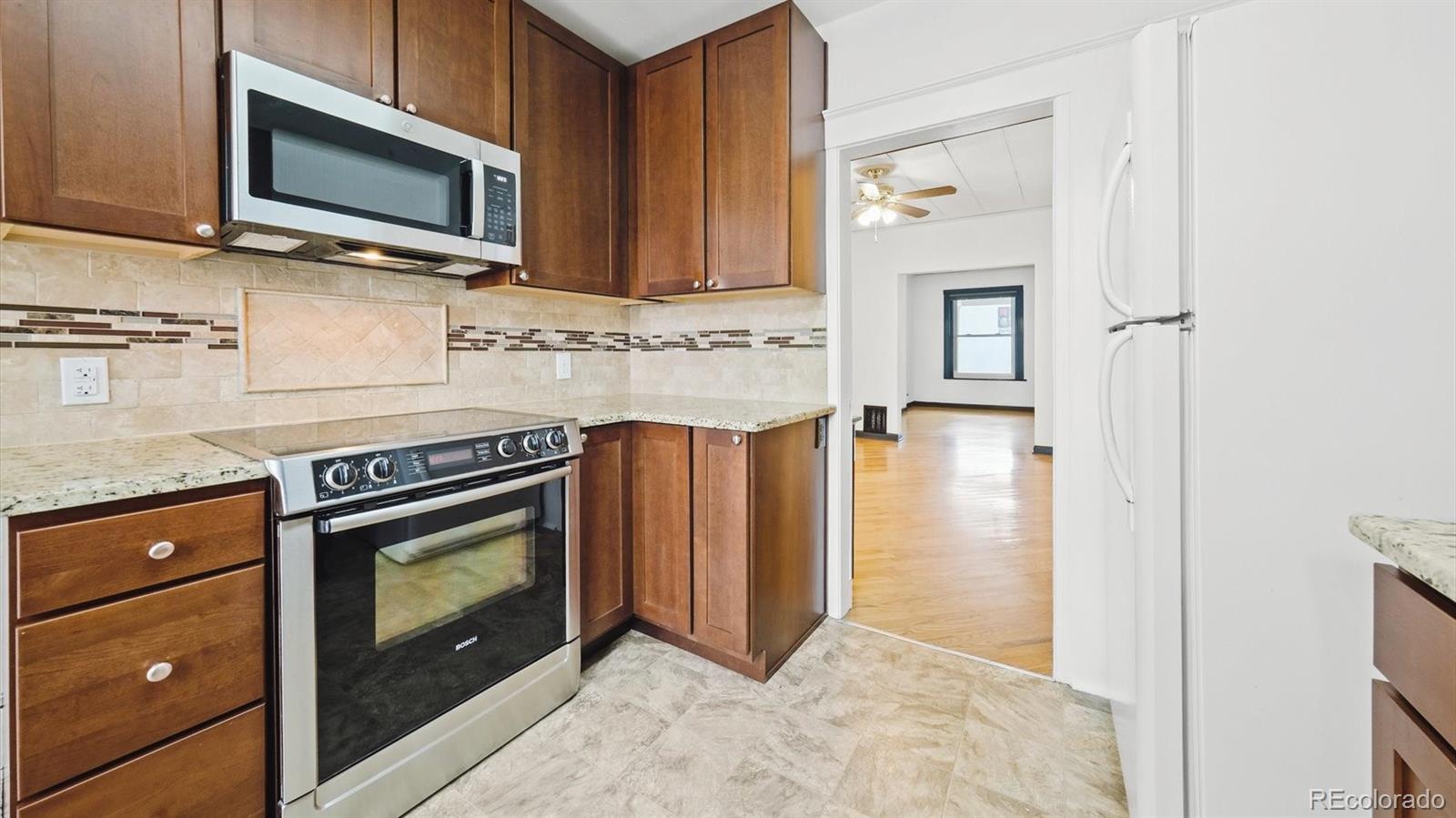 553 Logan Street Denver, CO 80203 - Photo 19 of 38 a kitchen with stainless steel appliances granite countertop a stove microwave and sink