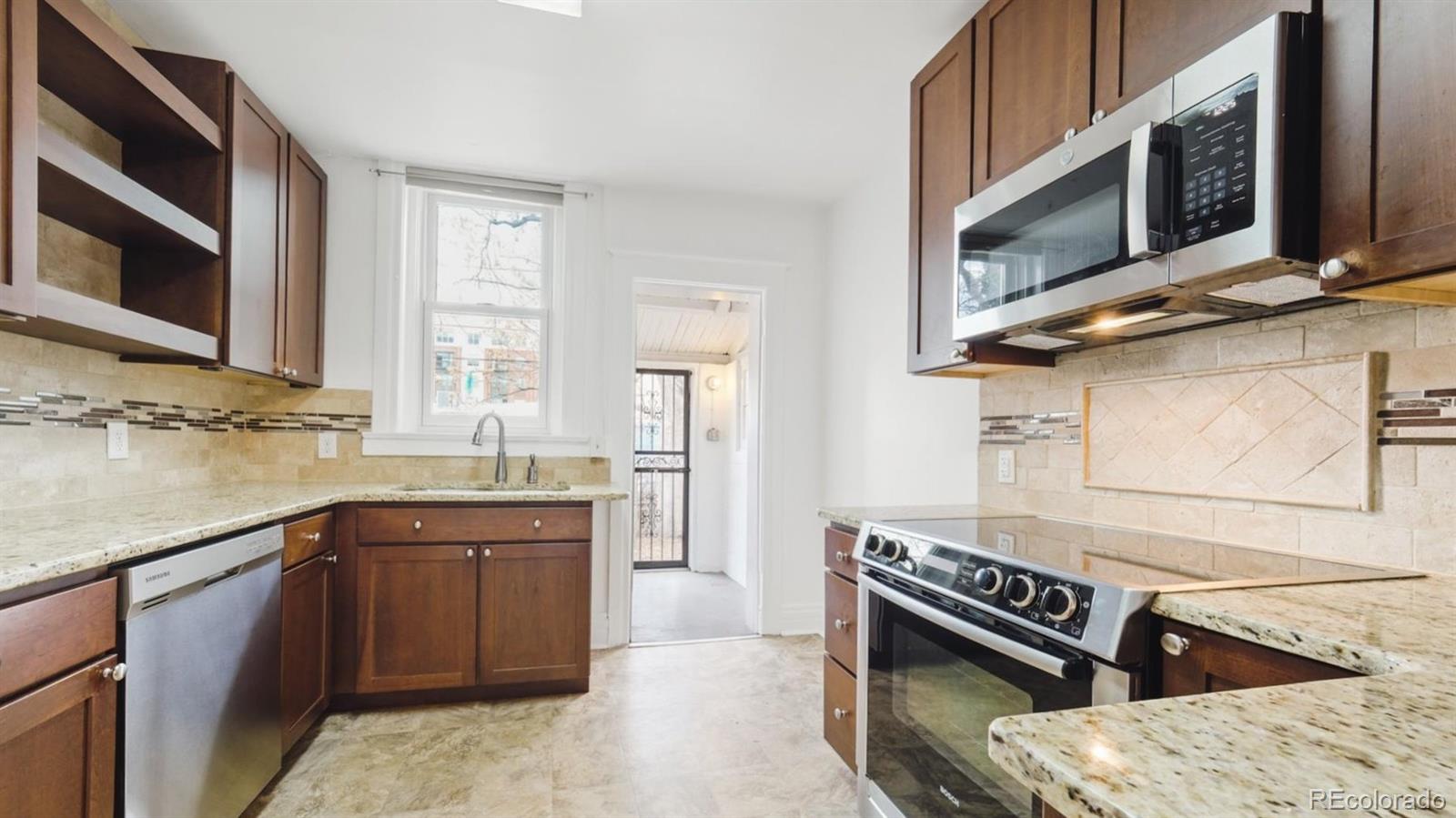 553 Logan Street Denver, CO 80203 - Photo 6 of 38 a kitchen with stainless steel appliances granite countertop a sink and stove top oven