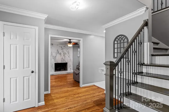 a view of an empty room with wooden floor and a ceiling fan