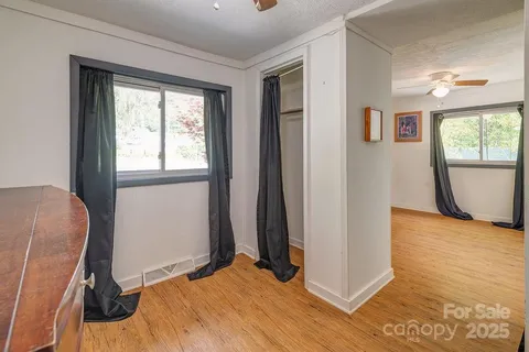 a view of an empty room with window a ceiling fan and wooden floor