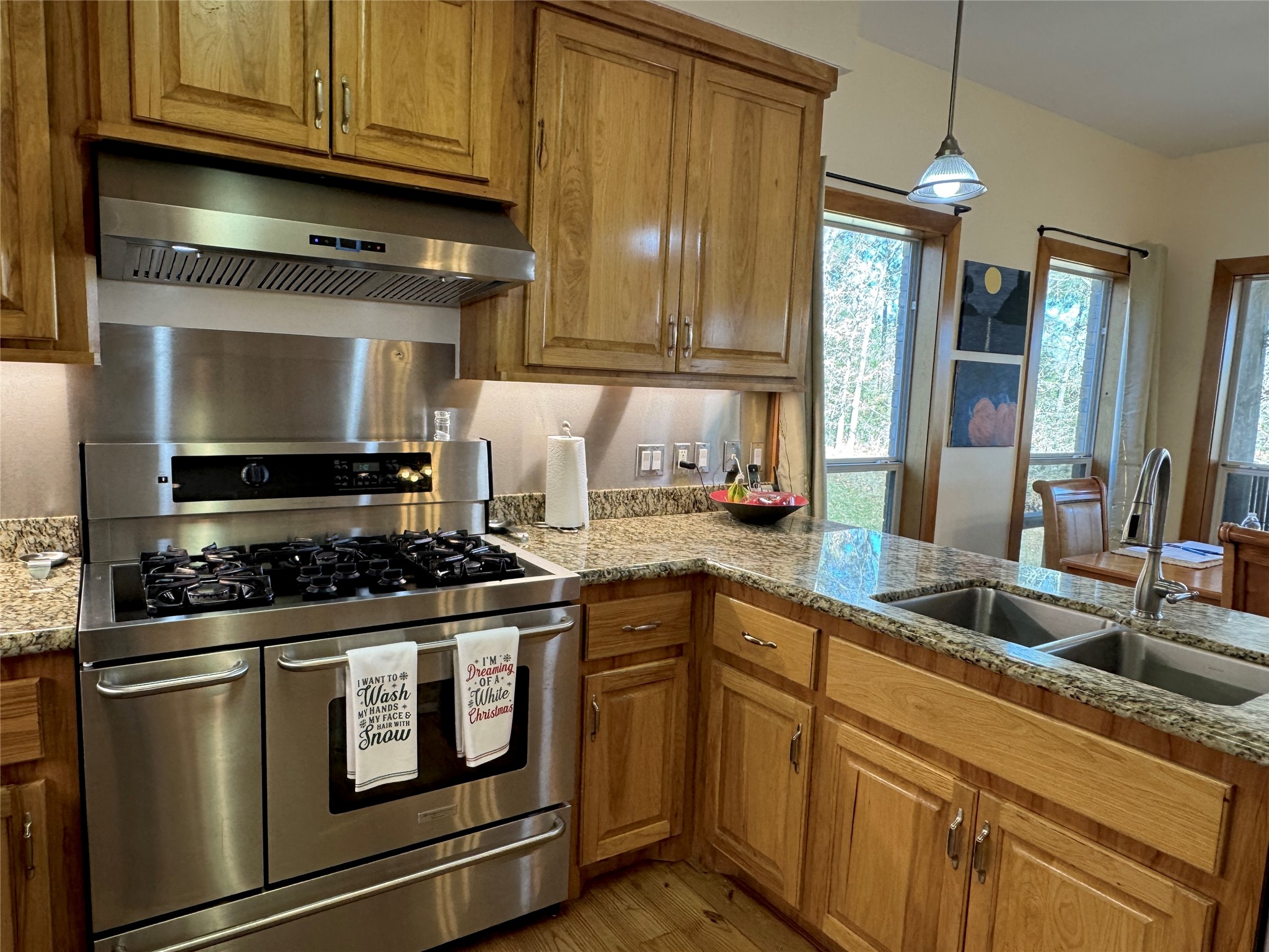 55 Lake Road Huntsville, TX 77320 - Photo 10 of 50 This kitchen features stainless steel appliances, including a gas cooktop and electric double oven. The room has granite countertops, wooden cabinetry, and a double sink. Large windows provide lots of natural light