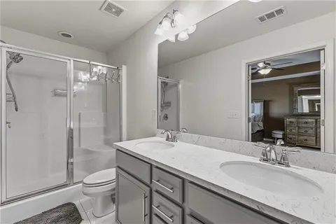 a bathroom with a granite countertop sink toilet a large mirror a shower and vanity