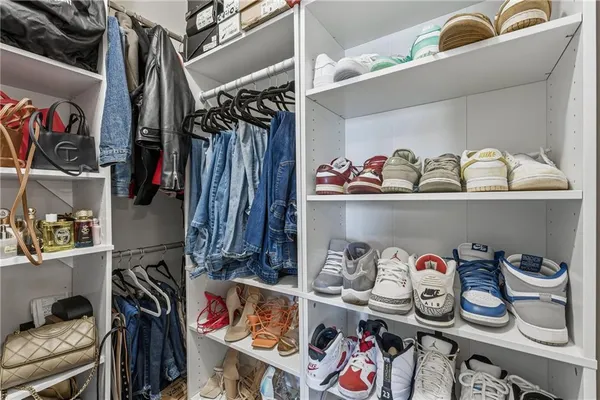 a view of walk in closet with clothes and shoes