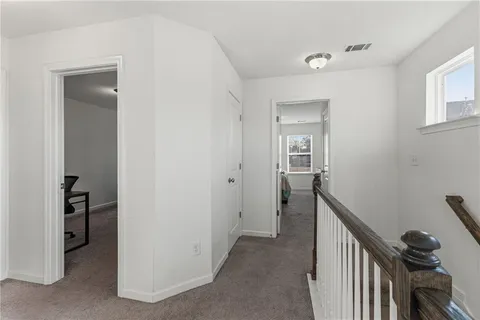 a view of a hallway to a livingroom with wooden floor and stairs