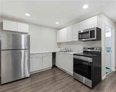a kitchen with granite countertop white cabinets and stainless steel appliances
