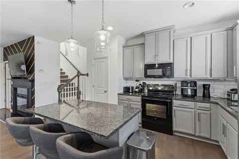 a kitchen with stainless steel appliances granite countertop a stove a sink dishwasher a dining table and chairs with wooden floor