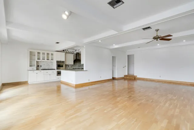 a kitchen with a sink dishwasher a stove and white cabinets with wooden floor