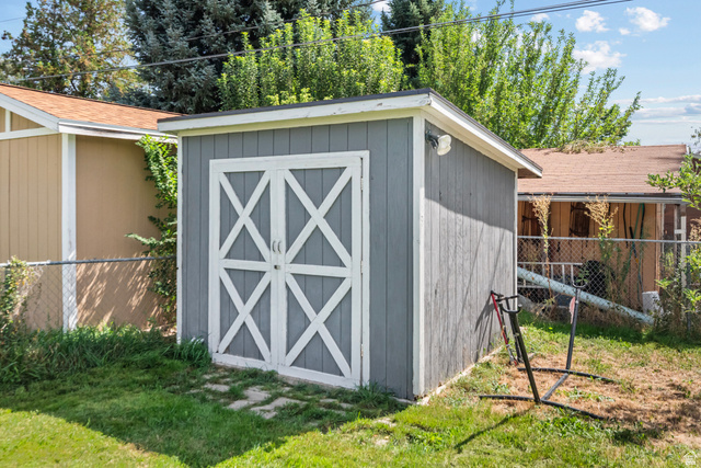 564 Swenson Avenue Springville, UT 84663 - Photo 23 of 26 Detached storage shed featuring a gray exterior, white cross-brace doors, and a partial chain-link fence