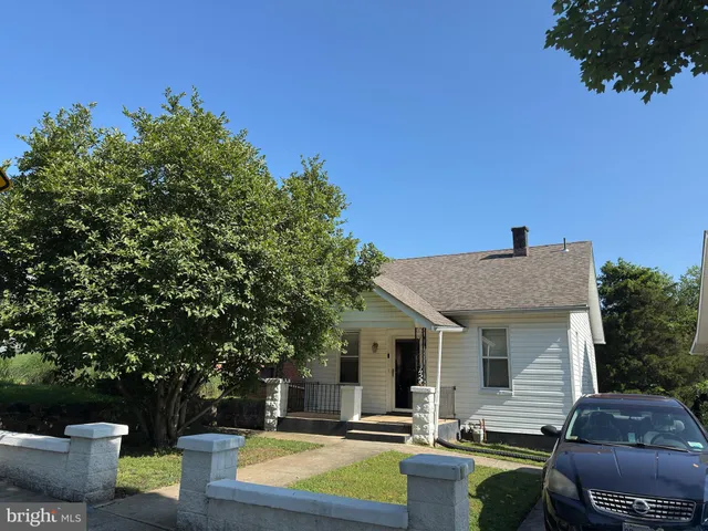 a view of a patio with couches table and chairs under an umbrella with large trees