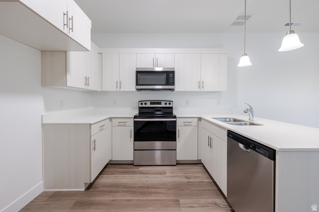 4661 Poplar Way, Unit R304 Mapleton, UT 84664 - Photo 11 of 17 Kitchen featuring stainless steel appliances, a peninsula, light wood finished floors, pendant lighting, and white cabinets