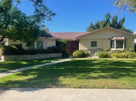 a backyard of a house with potted plants and large tree