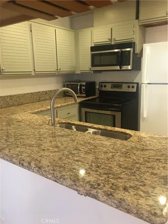 a kitchen with stainless steel appliances a sink a stove a microwave and a refrigerator