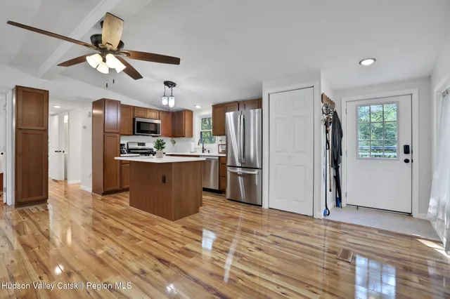 a kitchen with stainless steel appliances kitchen island granite countertop a refrigerator a stove a sink dishwasher and a refrigerator with wooden floor