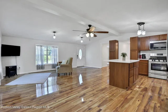 a living room with couches and kitchen view with wooden floor