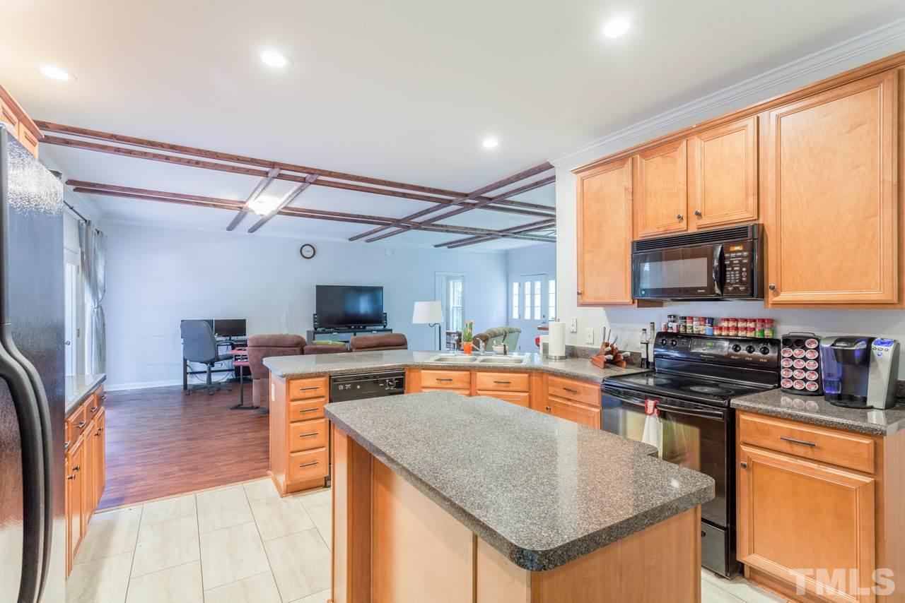 2092 Suitts Store Road Franklinton, NC 27525 - Photo 5 of 21 a kitchen with stainless steel appliances granite countertop a stove top oven a sink a dining table and chairs with wooden floor