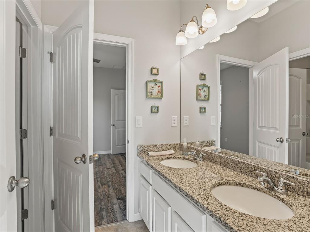 5626 Southwest 50th Court Ocala, FL 34474 - Photo 19 of 33 a bathroom with a granite countertop double vanity sink a mirror and a shower