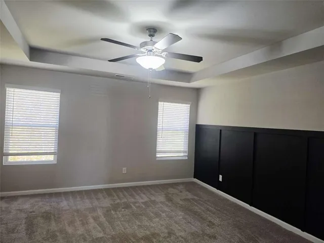 a view of an empty room with window and chandelier fan