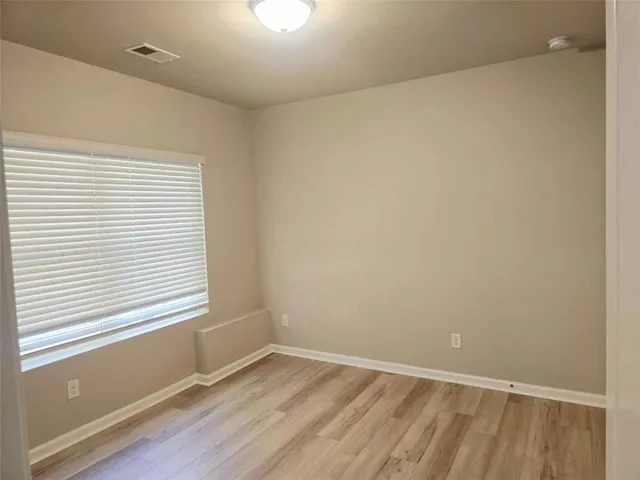 a view of wooden floor in an empty room with a window