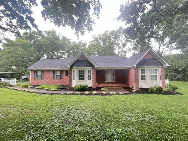 a front view of a house with a yard and trees