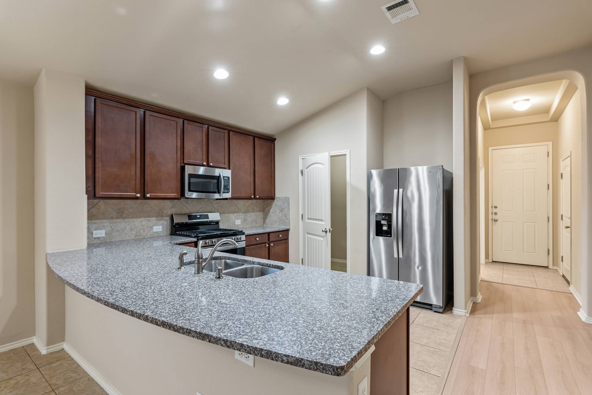 180 Fletcher Bend Buda, TX 78610 - Photo 8 of 36 a kitchen with stainless steel appliances granite countertop a refrigerator a stove and a sink with wooden cabinets