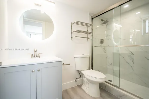 a bathroom with a toilet sink vanity and shower