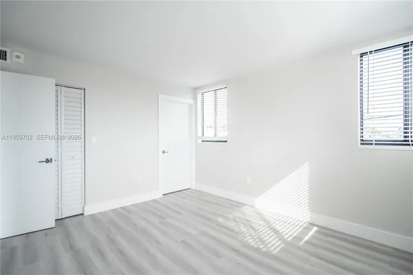 an empty room with wooden floor and windows