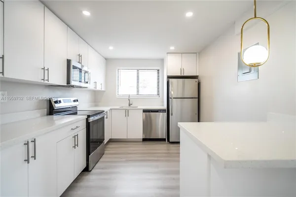 a kitchen with a sink a refrigerator and cabinets