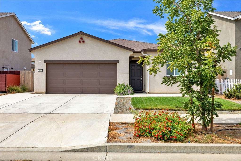 a white house with a tree and flower plants