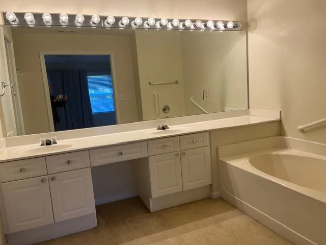 a spacious bathroom with a tub sink and mirror