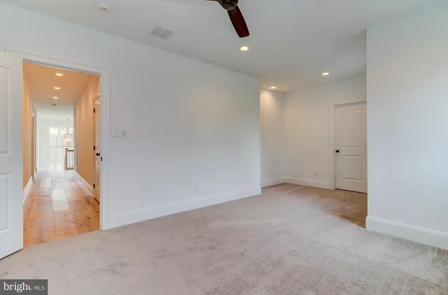 an empty room with chandelier fan and windows