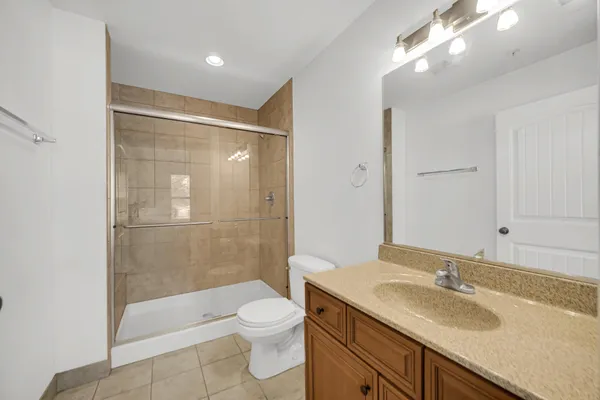 a bathroom with a granite countertop sink a toilet and shower