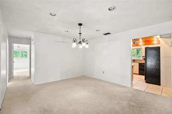 an empty room with a chandelier fan and windows