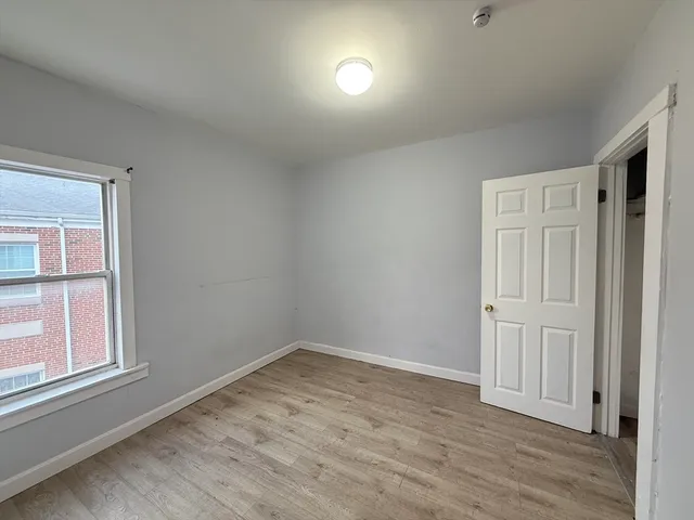 an empty room with wooden floor cabinet and windows