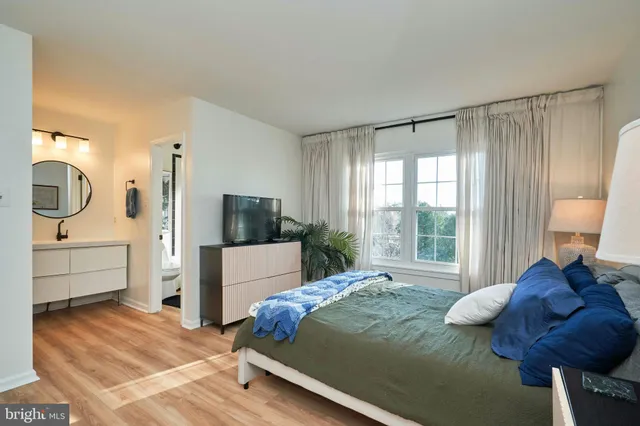 a bedroom with a bed a mirror and a large window