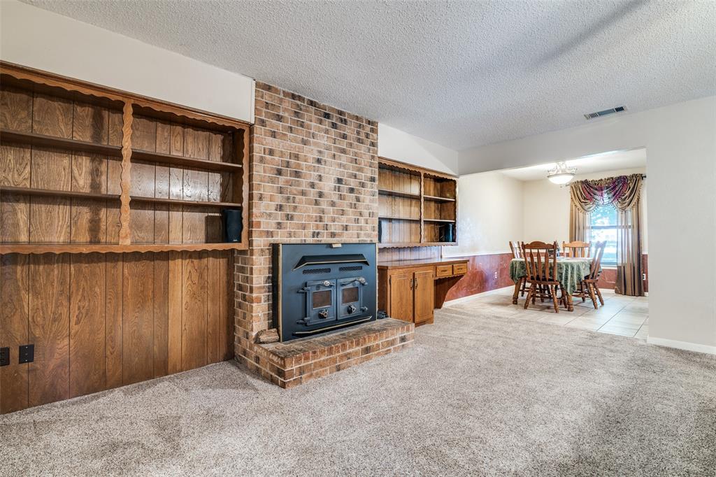 805 Paul Wilson Road Wylie, TX 75098 - Photo 12 of 38 Large living room includes a brick wood burning fireplace with blower and a wall of bookshelves providing plenty of storage space.