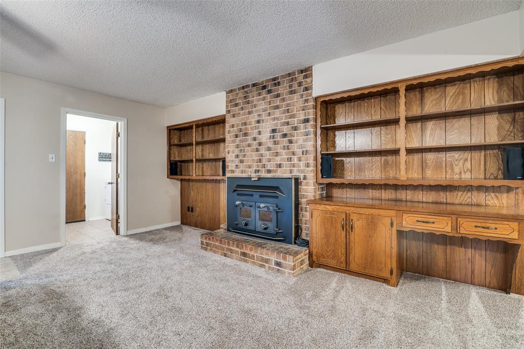 805 Paul Wilson Road Wylie, TX 75098 - Photo 13 of 38 Large living room includes a brick wood burning fireplace with blower and a wall of bookshelves providing plenty of storage space.