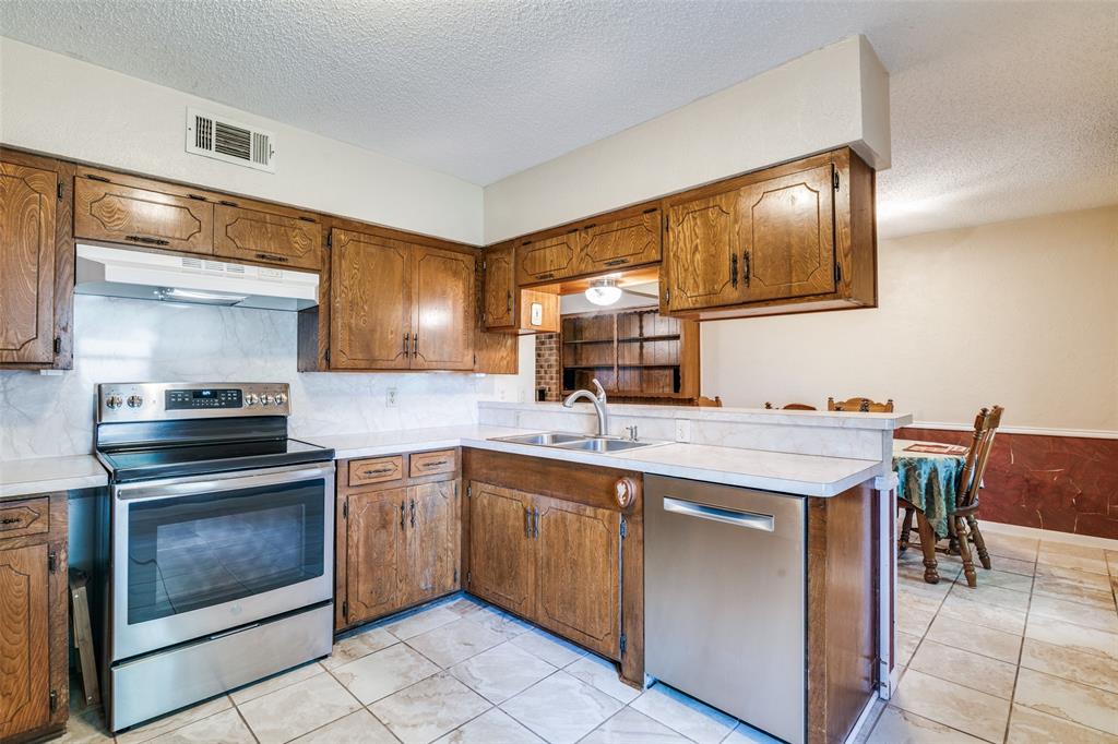 805 Paul Wilson Road Wylie, TX 75098 - Photo 15 of 38 Kitchen features a breakfast bar, stainless steel appliances, ample cabinets, and tile flooring.