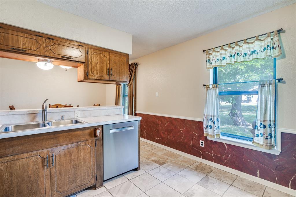 805 Paul Wilson Road Wylie, TX 75098 - Photo 16 of 38 Kitchen features a breakfast bar, stainless steel appliances, ample cabinets, and tile flooring.
